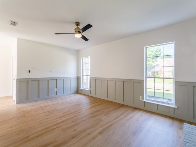 unfurnished room with a wealth of natural light, light hardwood / wood-style flooring, and ceiling fan