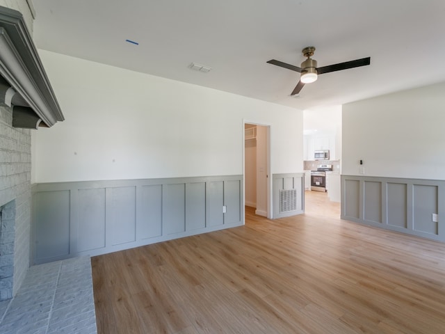 unfurnished living room featuring ceiling fan, light hardwood / wood-style flooring, and a brick fireplace