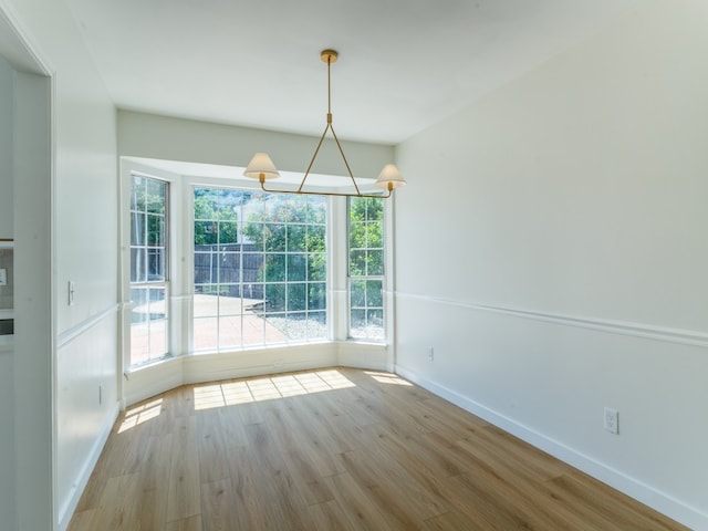 unfurnished dining area with light wood-type flooring and a notable chandelier