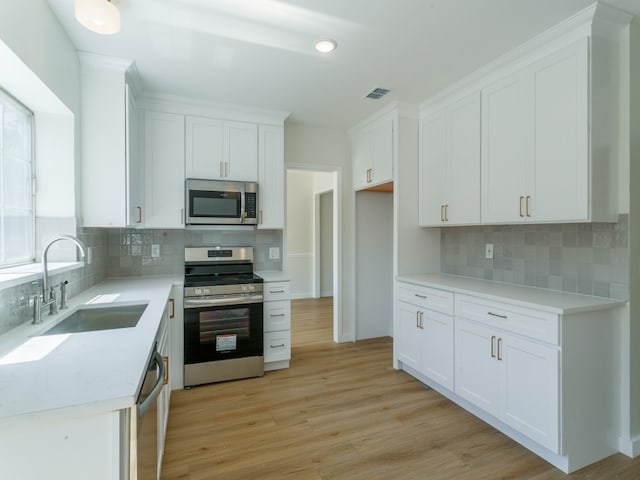 kitchen featuring white cabinetry, appliances with stainless steel finishes, sink, and light wood-type flooring