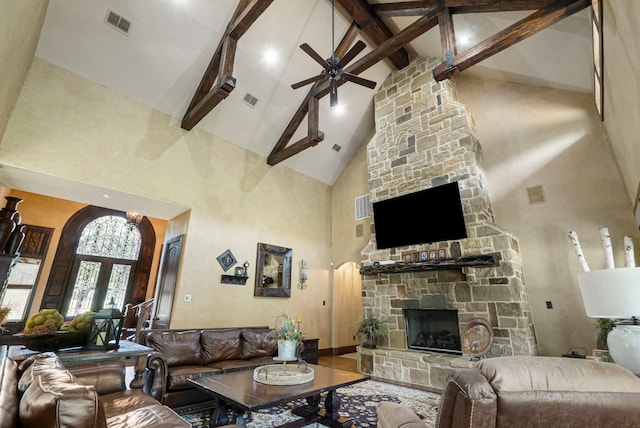 living room featuring ceiling fan, a stone fireplace, high vaulted ceiling, hardwood / wood-style flooring, and beamed ceiling