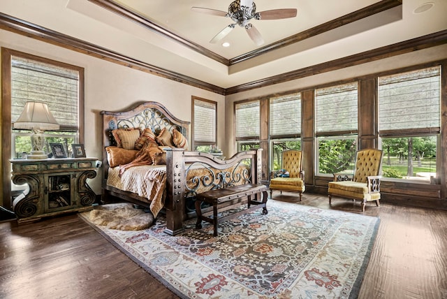 bedroom with ceiling fan, a raised ceiling, crown molding, and dark hardwood / wood-style flooring