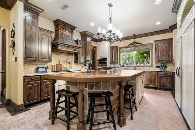 kitchen with wood counters, decorative backsplash, a kitchen island with sink, and custom exhaust hood