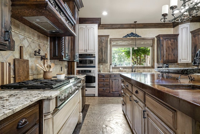 kitchen with decorative backsplash, premium range hood, light tile patterned floors, crown molding, and double oven