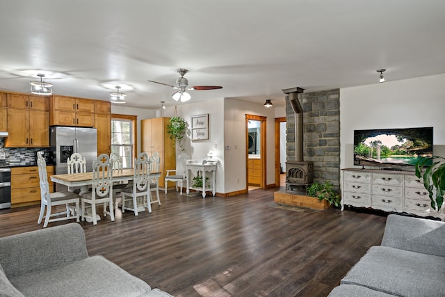 living room with ceiling fan, dark hardwood / wood-style floors, a wood stove, and washer / clothes dryer