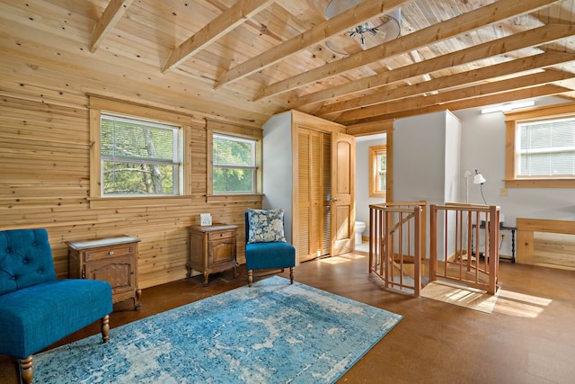 living area with beam ceiling, wood walls, and wood ceiling