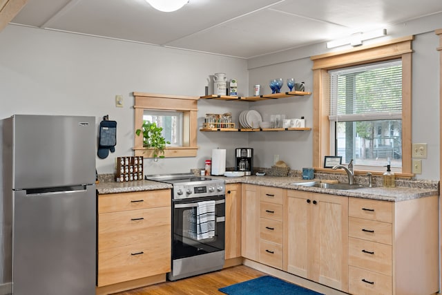 kitchen with light brown cabinets, light hardwood / wood-style flooring, light stone counters, sink, and stainless steel appliances