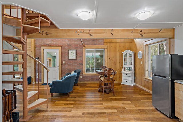 interior space with light wood-type flooring, wood walls, and brick wall