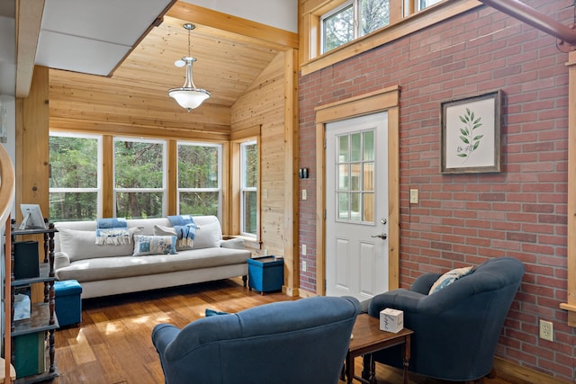 living room featuring hardwood / wood-style flooring, wooden walls, high vaulted ceiling, and brick wall