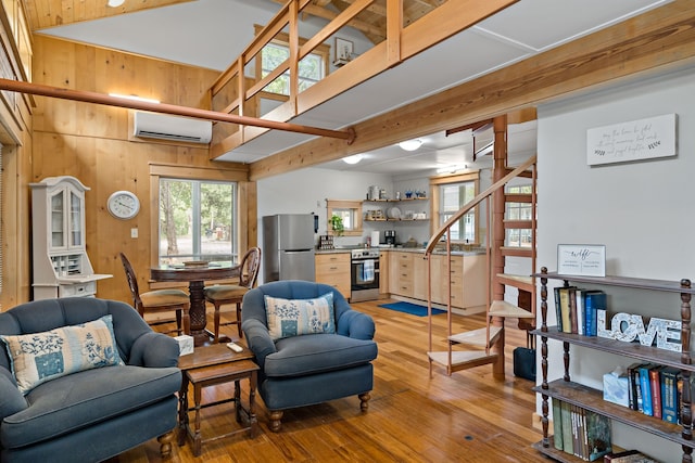 living room featuring high vaulted ceiling, wooden walls, hardwood / wood-style flooring, and a wall mounted air conditioner