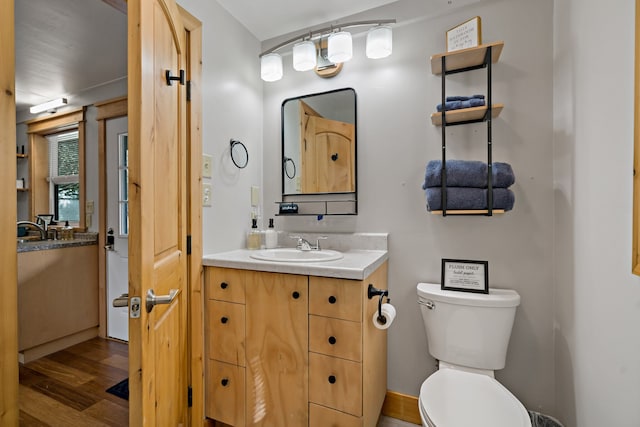 bathroom with toilet, vanity, and hardwood / wood-style flooring