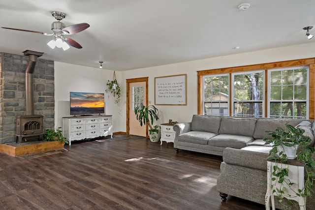 living room with ceiling fan, dark wood-type flooring, and a wood stove