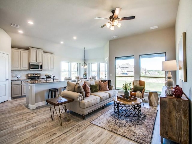 living room with ceiling fan, sink, and a healthy amount of sunlight