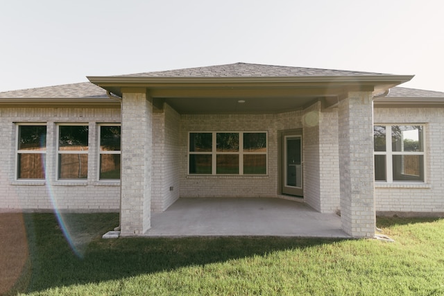 back of property with a lawn and a patio