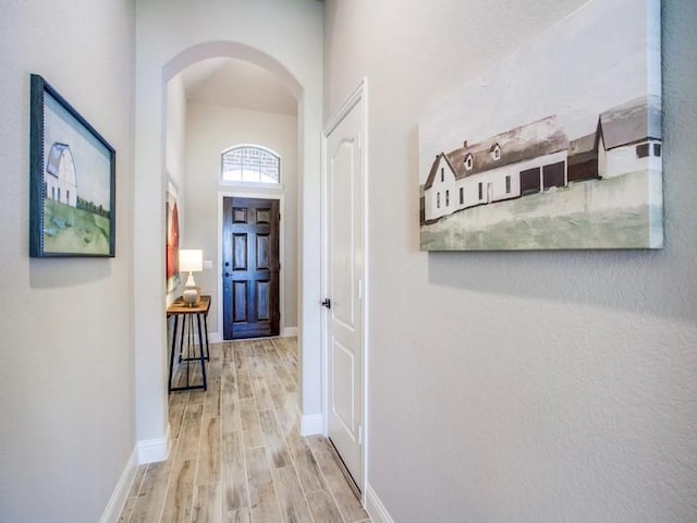 hall with light hardwood / wood-style floors and a high ceiling