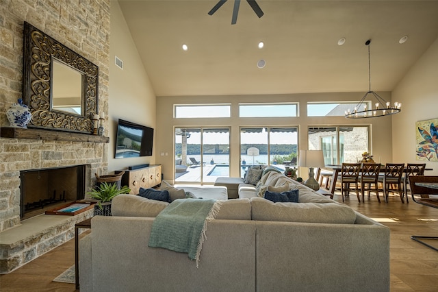 living room featuring a fireplace, high vaulted ceiling, hardwood / wood-style floors, and a chandelier