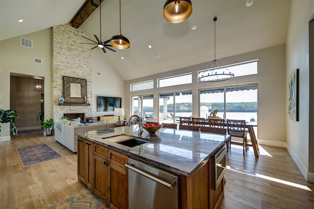 kitchen featuring light wood-type flooring, stainless steel dishwasher, high vaulted ceiling, and a kitchen island with sink