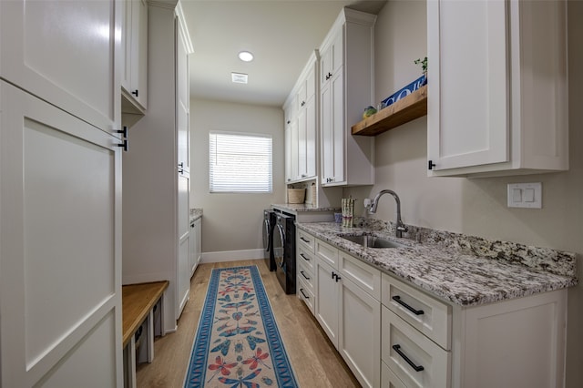 kitchen with sink, light wood-type flooring, white cabinetry, and light stone counters