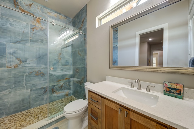 bathroom featuring a shower with door, toilet, and vanity