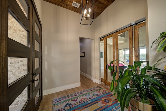 foyer entrance featuring high vaulted ceiling, hardwood / wood-style floors, a chandelier, and wood ceiling