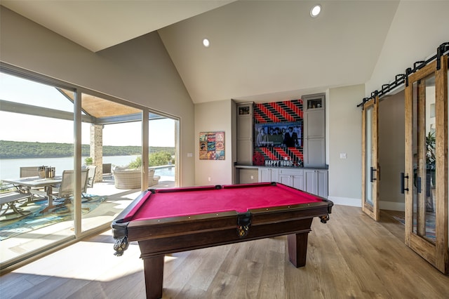 rec room with billiards, light hardwood / wood-style flooring, a water view, and a barn door