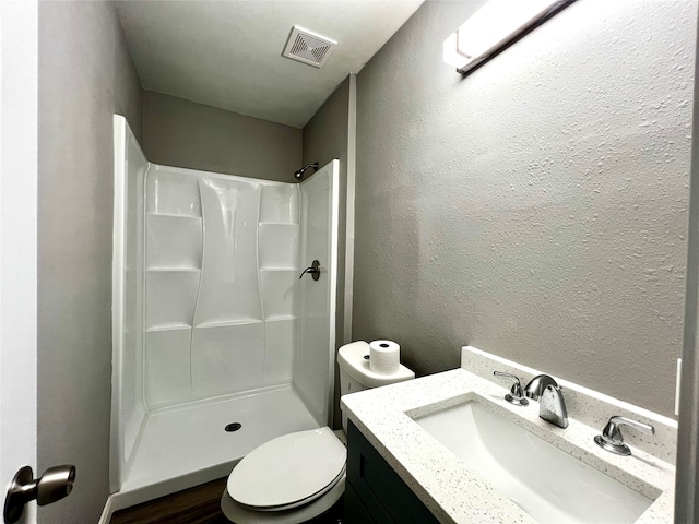 bathroom featuring toilet, vanity, and walk in shower