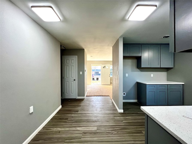 kitchen with light stone counters, dark colored carpet, and gray cabinets