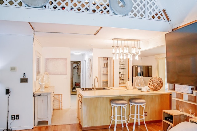 kitchen featuring light hardwood / wood-style flooring, decorative light fixtures, sink, kitchen peninsula, and a breakfast bar