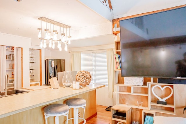 kitchen with light hardwood / wood-style flooring, stainless steel refrigerator, sink, pendant lighting, and a notable chandelier