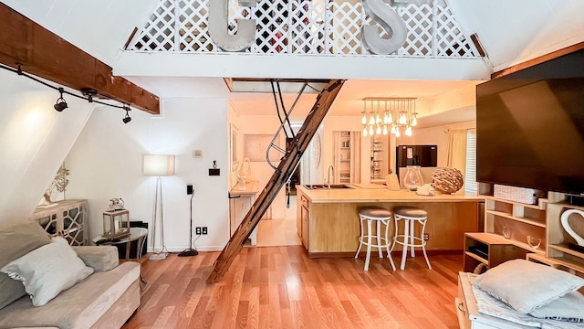 interior space featuring hardwood / wood-style flooring, a breakfast bar area, sink, and beamed ceiling