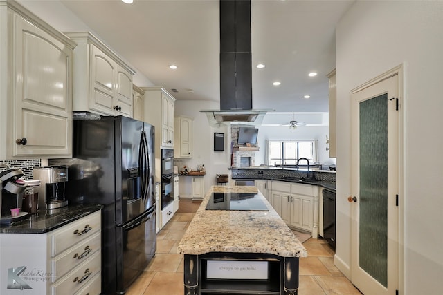 kitchen with dark stone counters, sink, ceiling fan, island range hood, and black appliances