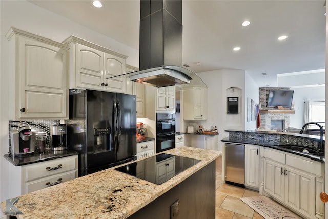 kitchen with dark stone counters, island exhaust hood, a fireplace, black appliances, and light tile patterned flooring