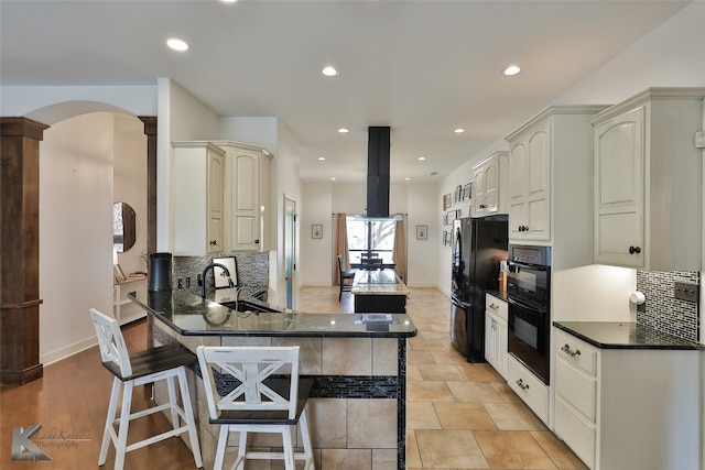 kitchen with backsplash, a breakfast bar area, sink, kitchen peninsula, and black appliances