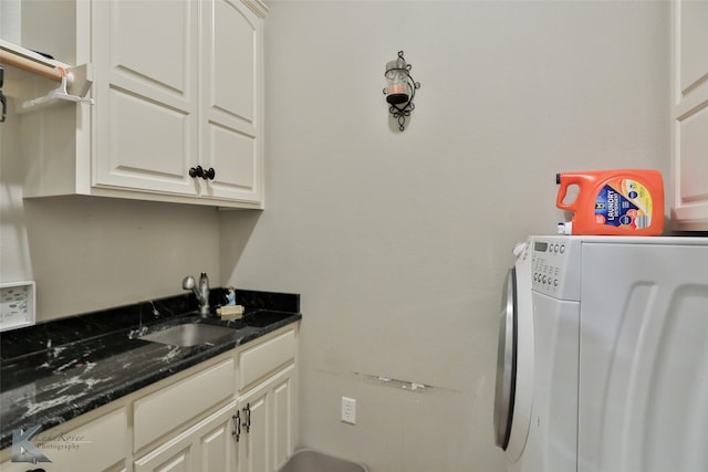 clothes washing area with sink, washer and clothes dryer, and cabinets