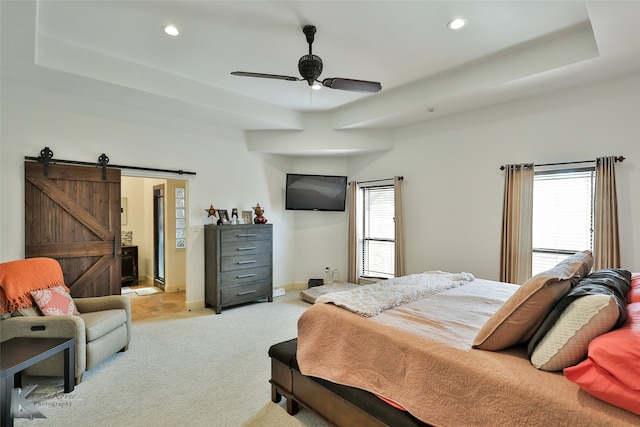 bedroom featuring ceiling fan, multiple windows, light carpet, and a barn door