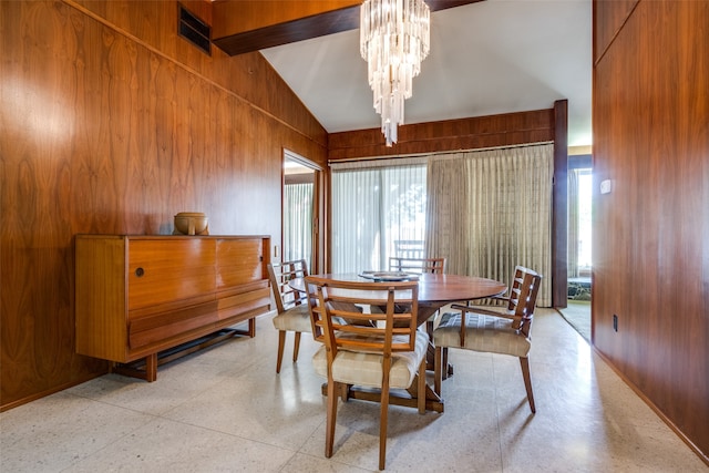 dining area featuring a chandelier, high vaulted ceiling, wooden walls, and a healthy amount of sunlight