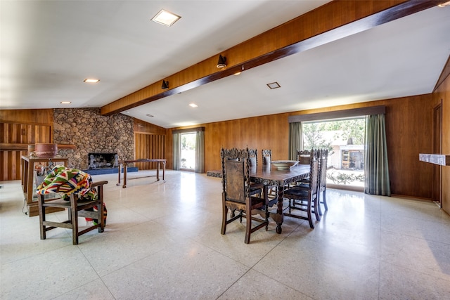 dining area with a wealth of natural light, wooden walls, a fireplace, and lofted ceiling with beams