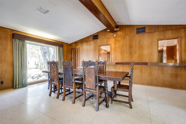 dining room with vaulted ceiling with beams and wooden walls