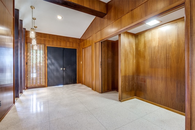 empty room with vaulted ceiling with beams and wooden walls