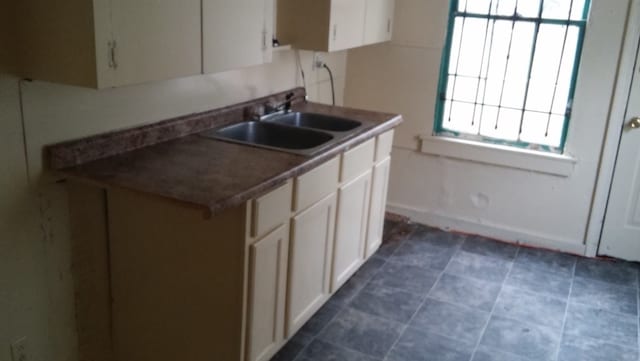 kitchen featuring sink, white cabinetry, and dark tile patterned floors