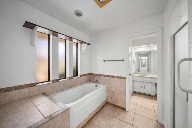 bathroom with tile patterned flooring, vanity, a tub to relax in, and tile walls