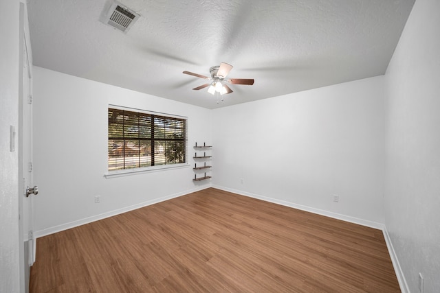 empty room with ceiling fan, a textured ceiling, and hardwood / wood-style flooring