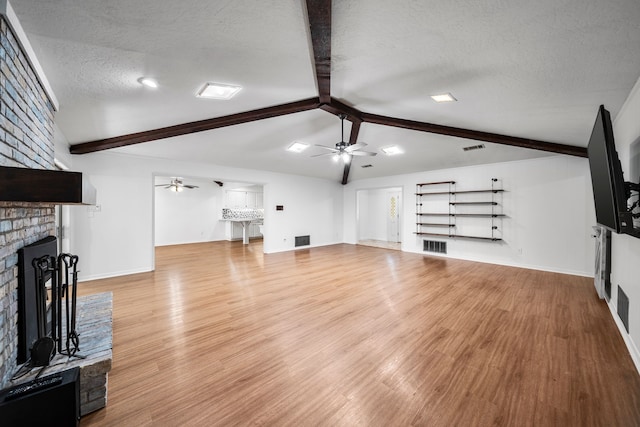 living room with lofted ceiling with beams, a textured ceiling, and light hardwood / wood-style floors