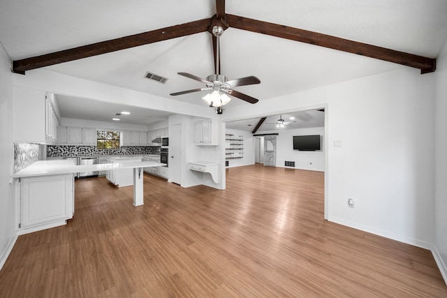 unfurnished living room featuring vaulted ceiling with beams, ceiling fan, and light wood-type flooring