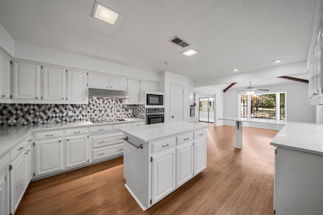 kitchen with backsplash, ceiling fan, black appliances, white cabinets, and a center island