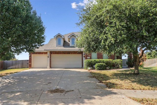 view of front of house featuring fence, driveway, a shingled roof, a garage, and brick siding