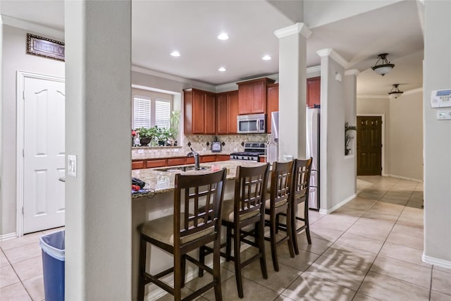 kitchen with a sink, stainless steel appliances, crown molding, light tile patterned floors, and decorative backsplash