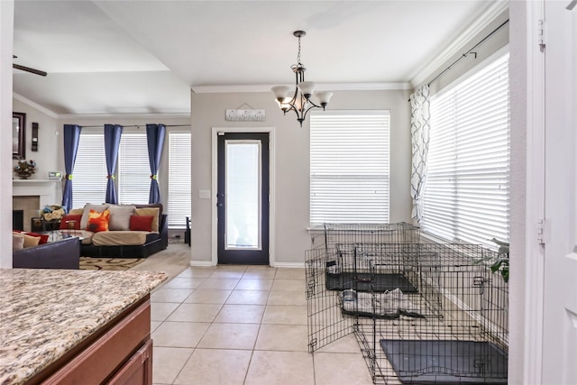 entryway with crown molding, baseboards, a tiled fireplace, light tile patterned floors, and a notable chandelier