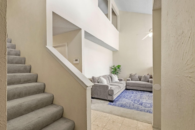 living room with ceiling fan, a towering ceiling, and light tile patterned floors