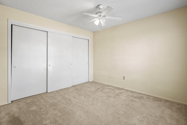 unfurnished bedroom with light carpet, a textured ceiling, a closet, and ceiling fan